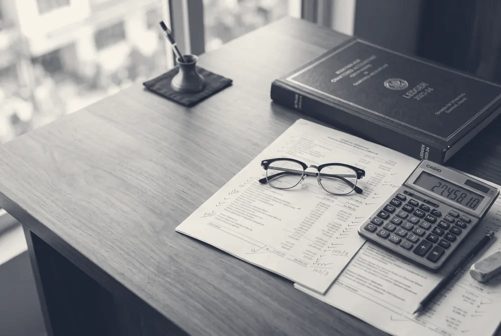 Printed financial statements with audit tick marks, calculator and ledger